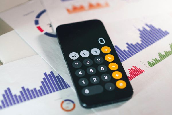 Smartphone-Taschenrechner liegt auf ausgedruckten Statistiken