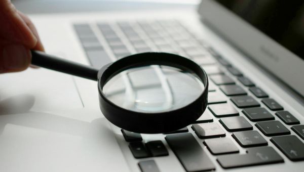 Une loupe est posée sur le clavier d'un ordinateur portable